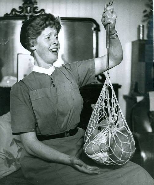 Медсестра Катриона Макаскилл взвешивает новорожденного ребенка, 1959 год, Шотландия